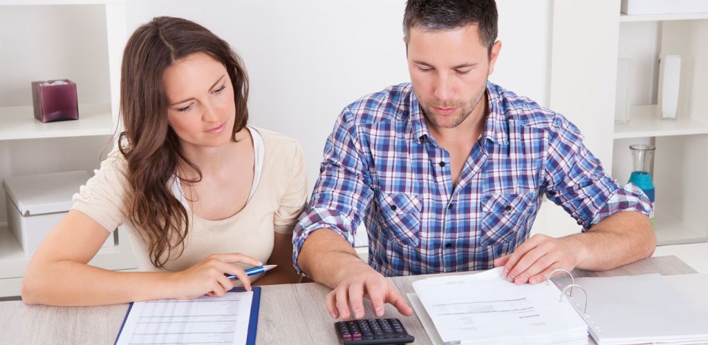 Two people at a desk using a calculator