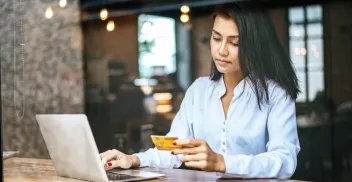 Woman at laptop looking at credit card