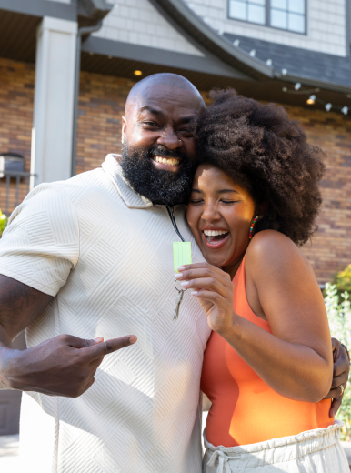 An excited couple hold the keys to their new home