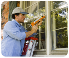 A man seals the cracks around the windows of a home