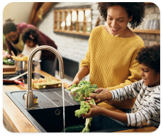 A mother and son wash produce in their kitchen sink