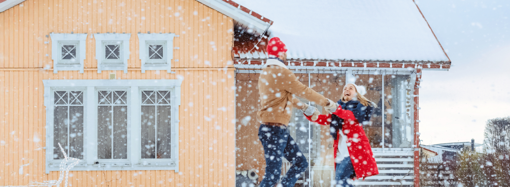 A couple playing in the snow in front of their home